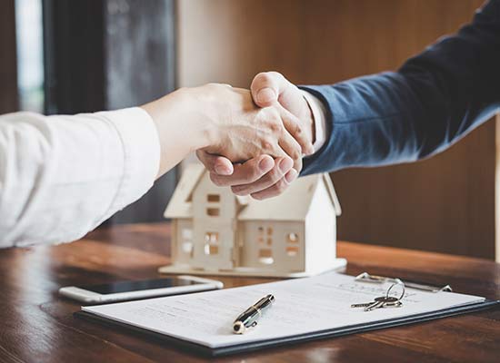 Handschlag mit Klienten beim Notar für Immobilienrecht in Linz Land mit unterzeichnetem Vertrag